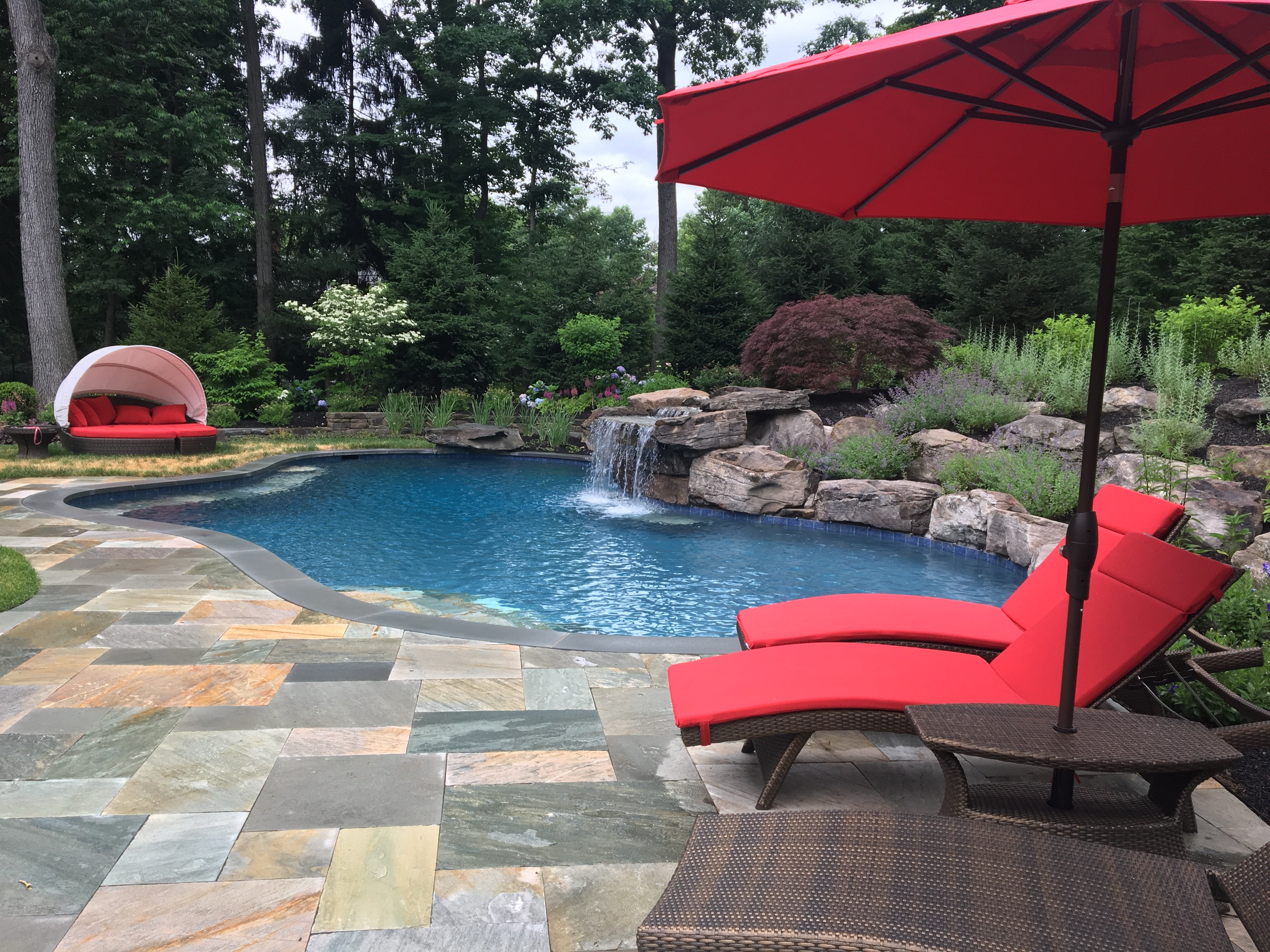 Freeform pool with rock waterfall and flagstone deck