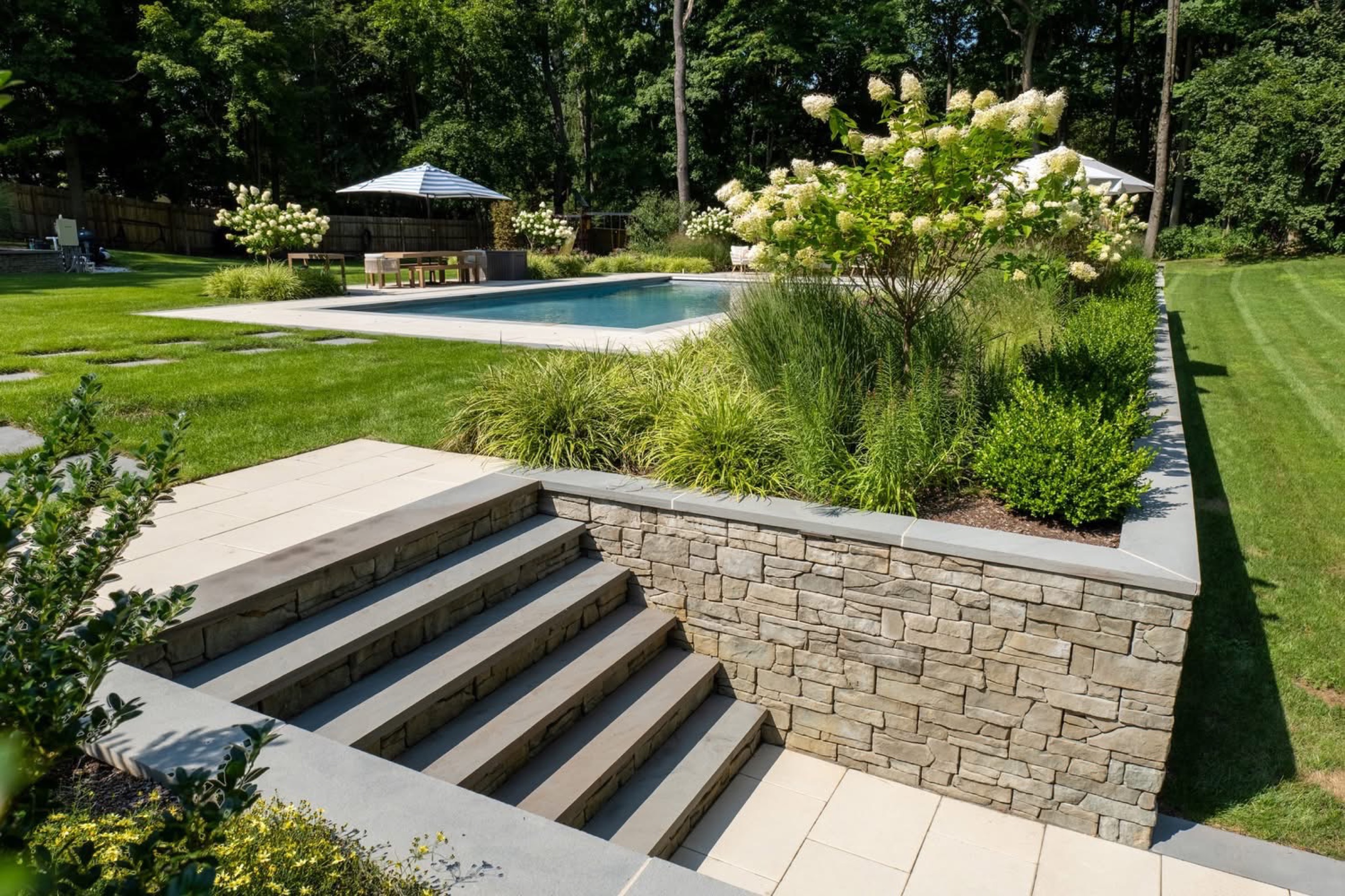 Hardscape steps and stone retaining wall with pool beyond