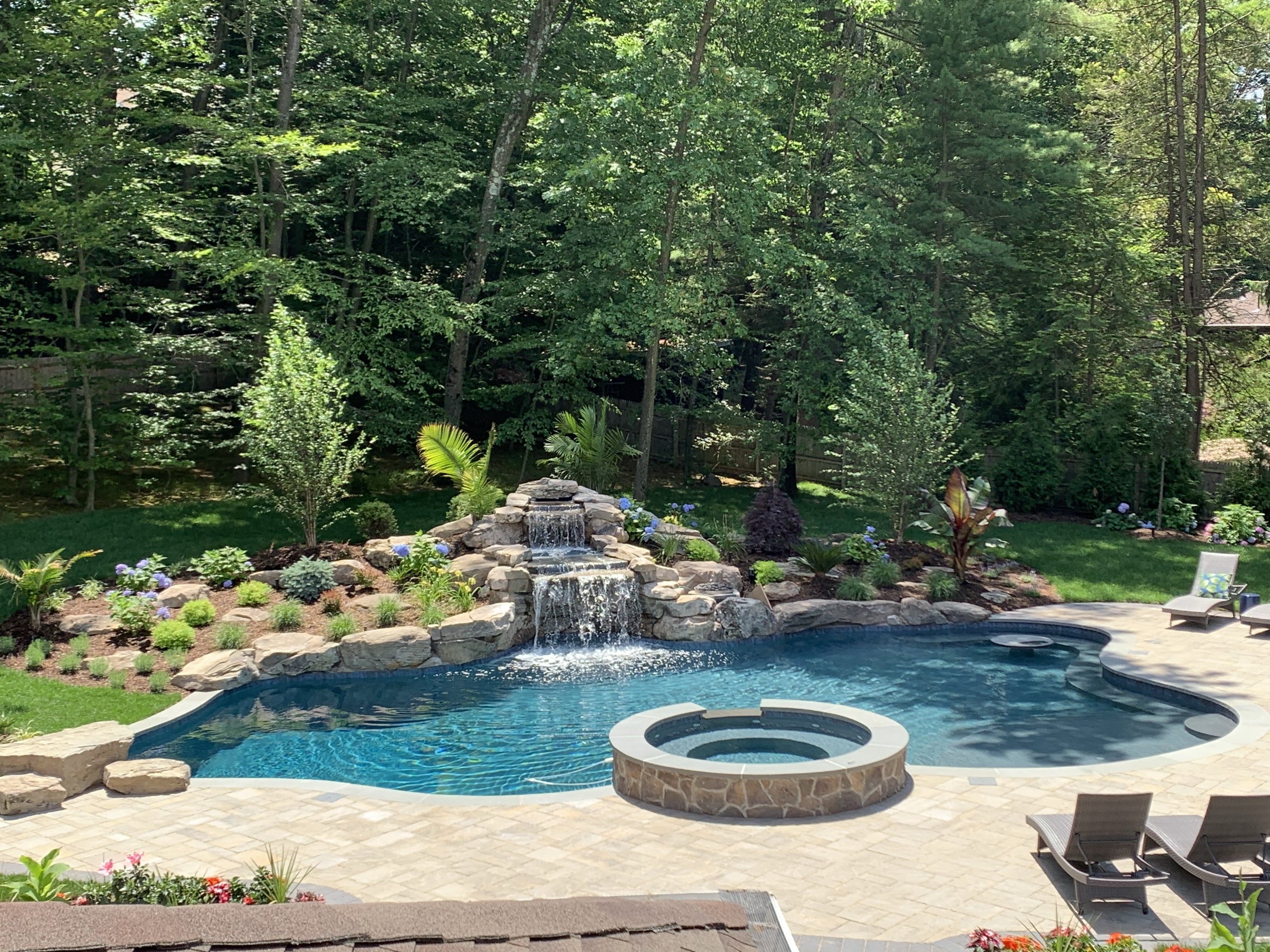 Freeform pool with rock waterfall and raised round spa
