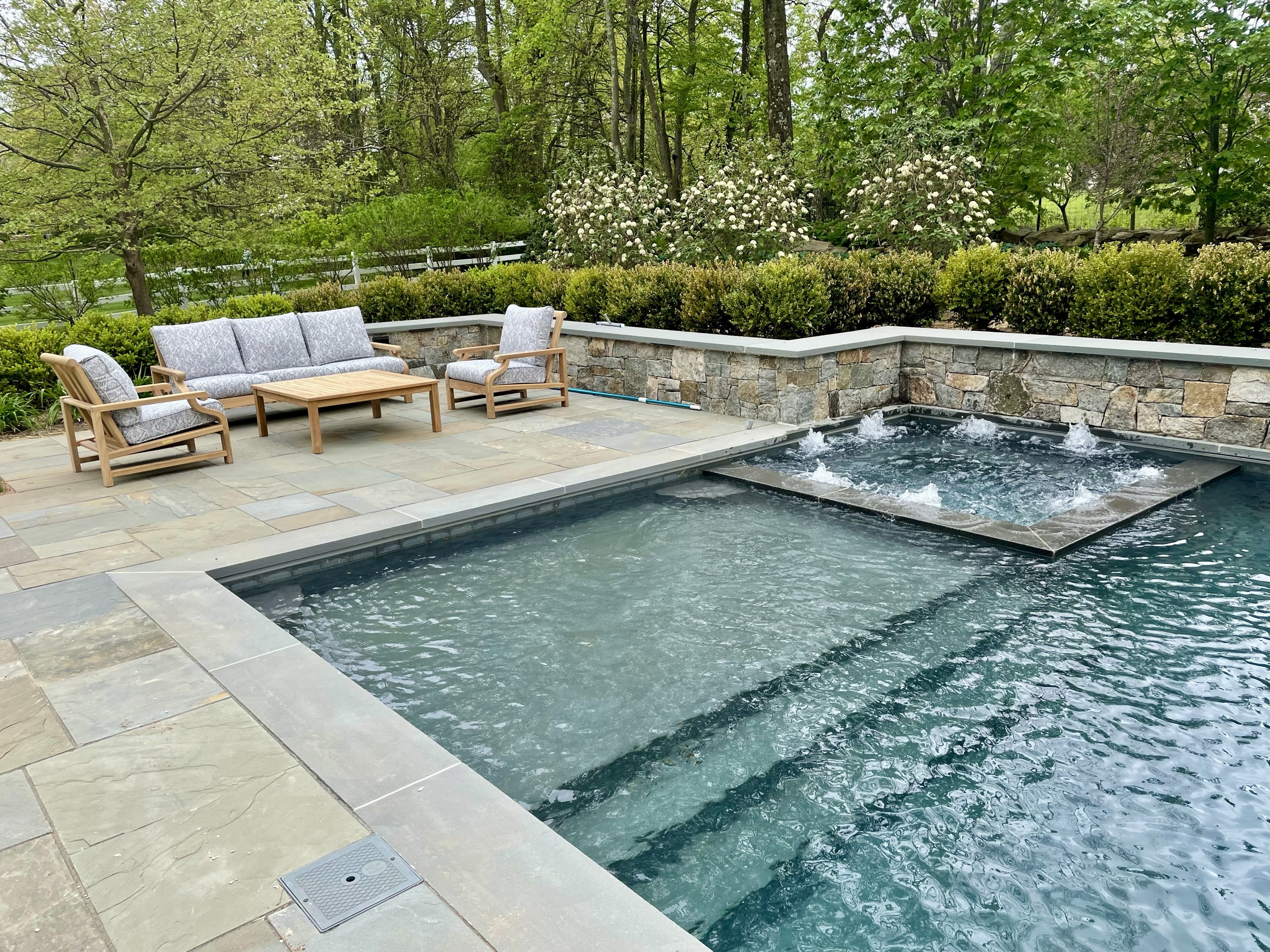 Geometric pool with attached spa and stone-wall scuppers