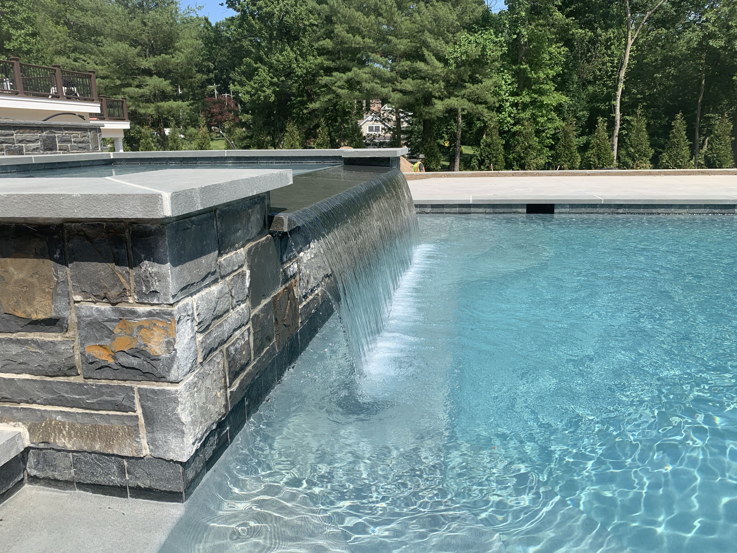 Sheer descent waterfall over stone-clad pool wall